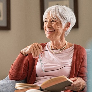 Senior woman smiling while reading at home