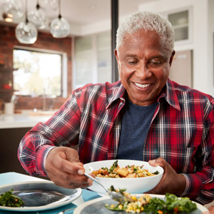 Senior man filling plate at table