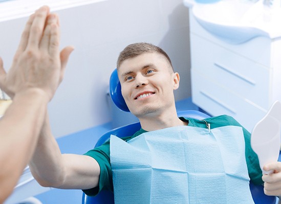 Colorado Springs patient high-fiving dentist after getting dental implants