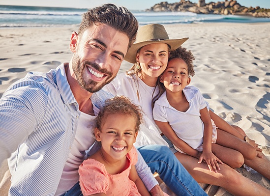 Patient smiling with family on beach after smile makeover