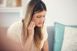 Woman holding jaw in pain.